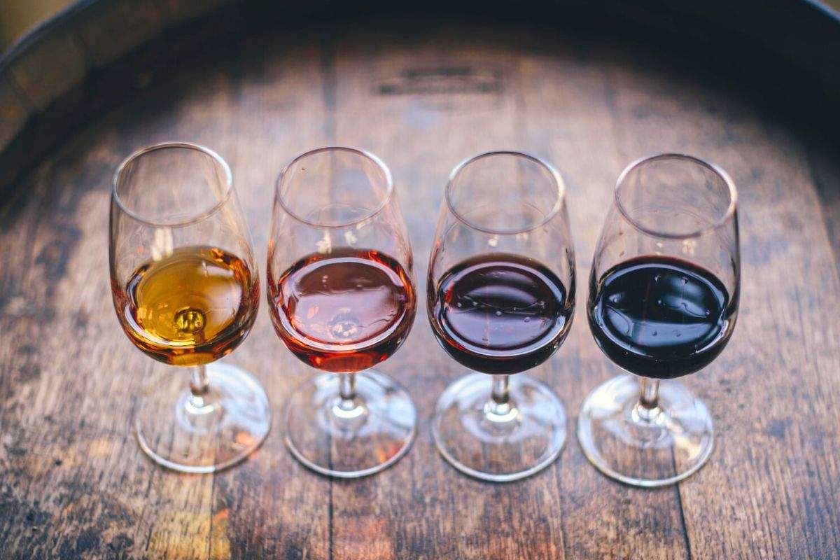 Taças de diferentes estilos de vinho de sobremesa em cima de um barril